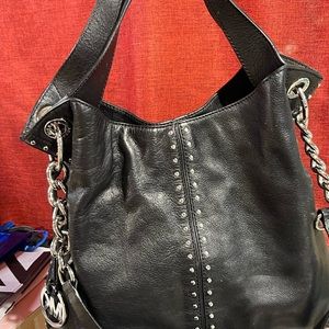 Black Micheal kors silver studded hobo bag with long and short handles.
